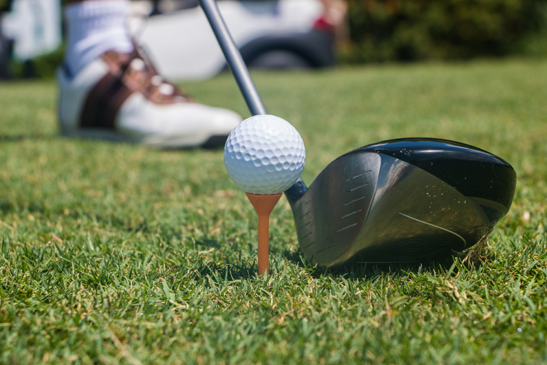 Golfer preparing to hit a white golf ball off of a tee.