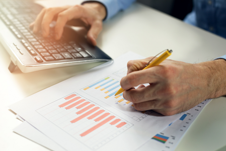 office clerk working with statistical reports and entering data into a computer