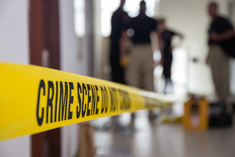 crime scene tape in building with blurred forensic team background