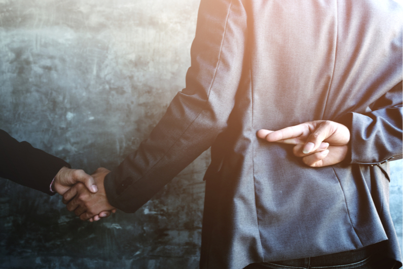 man shaking hands but crossing fingers behind his back